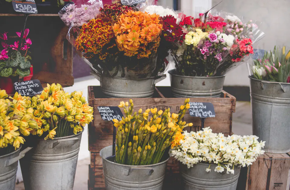 Baldes con flores frescas y precios escritos a mano en la entrada de una florería